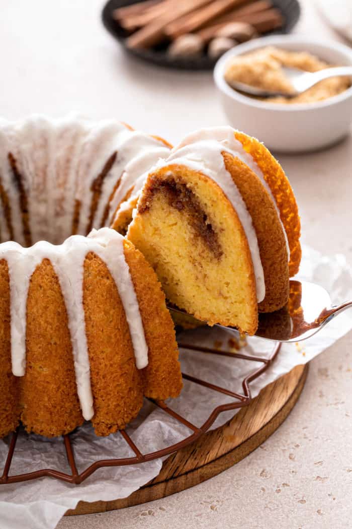 Cake server lifting up a slice of honey bun cake from the whole cake.