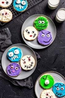 Halloween monster decorated sugar cookies arranged on three gray plates