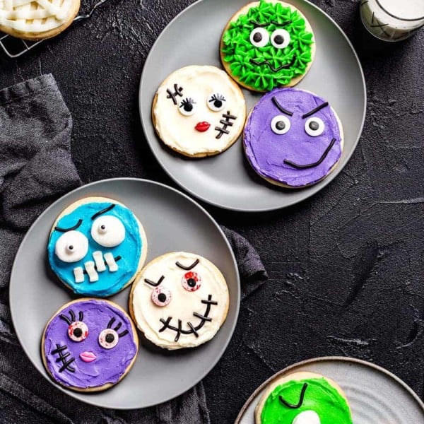Halloween monster decorated sugar cookies arranged on three gray plates