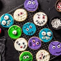 Sugar cookies decorated like halloween monsters on a wire rack