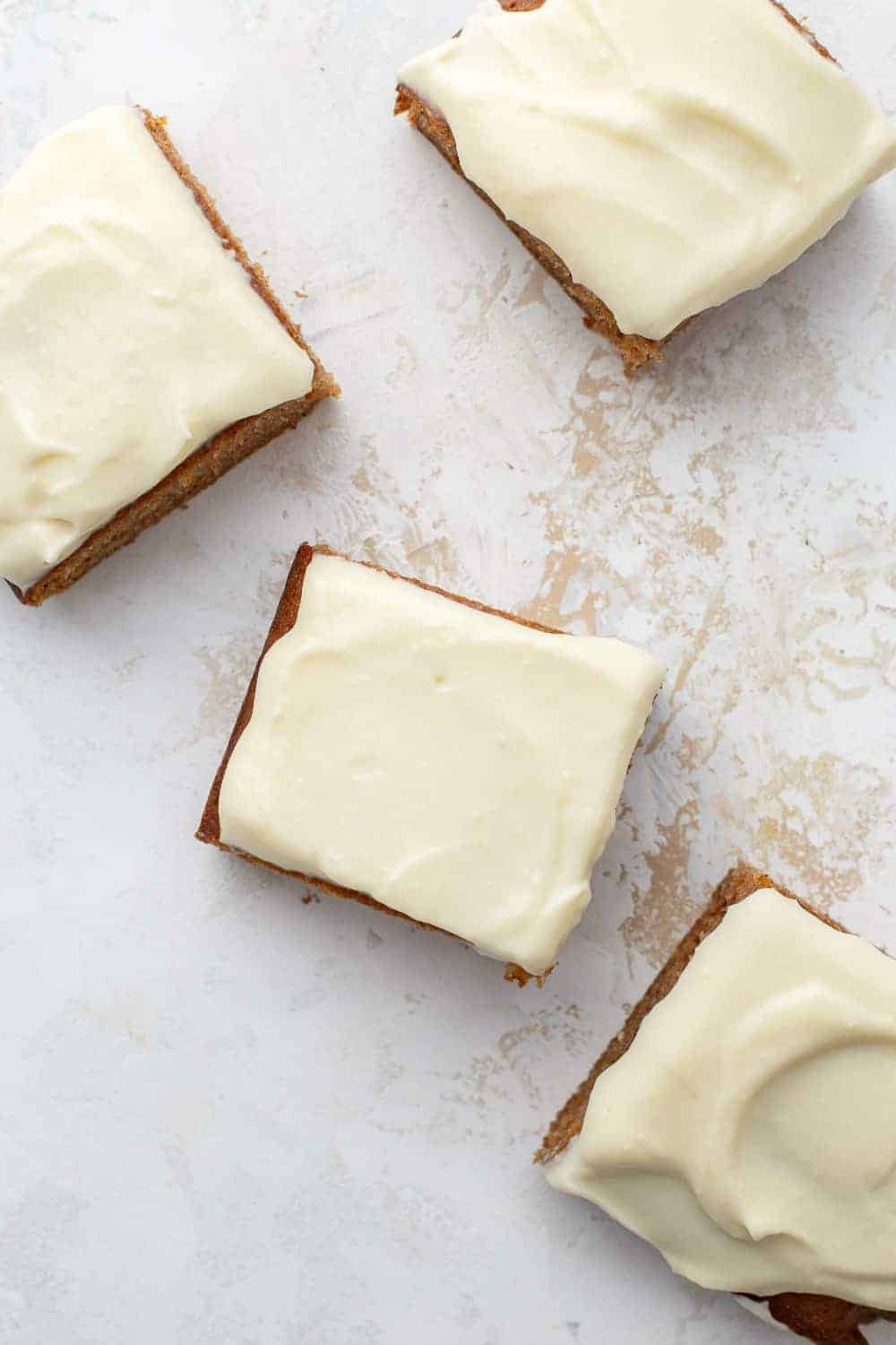 Pumpkin bars topped with cream cheese frosting, sliced and arranged on a countertop