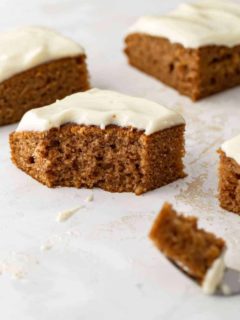 Side view of a pumpkin bar with cream cheese frosting with a bite taken out of it