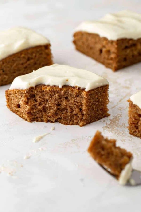 Side view of a pumpkin bar with cream cheese frosting with a bite taken out of it