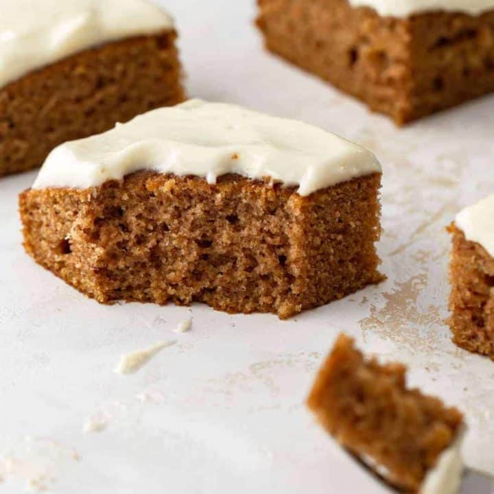 Side view of a pumpkin bar with cream cheese frosting with a bite taken out of it