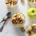 Glass dishes of Snickers Caramel Apple Salad next to candy bar pieces and granny smith apples