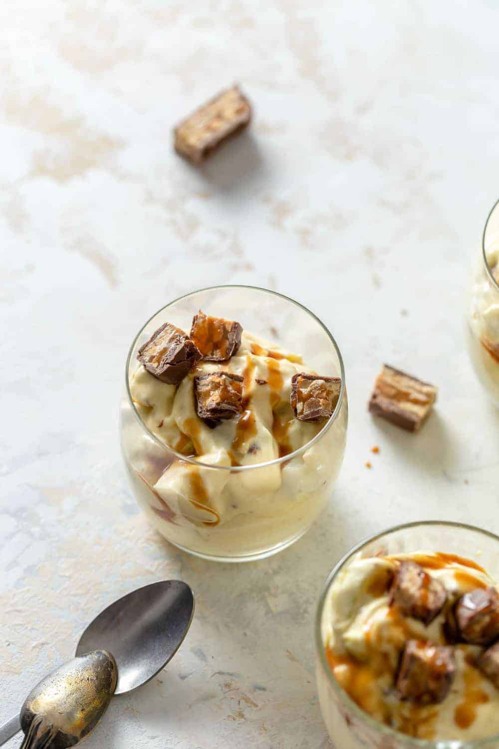 Spoon digging into a serving of Snickers Caramel Apple Salad in a glass bowl