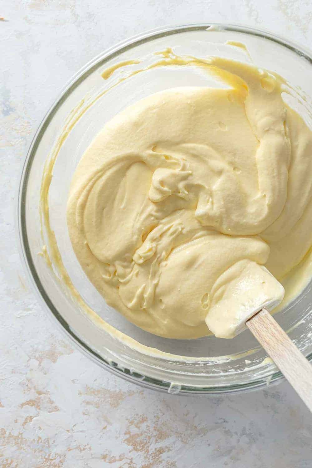 Pudding and cool whip mixture for caramel apple salad in a glass mixing bowl