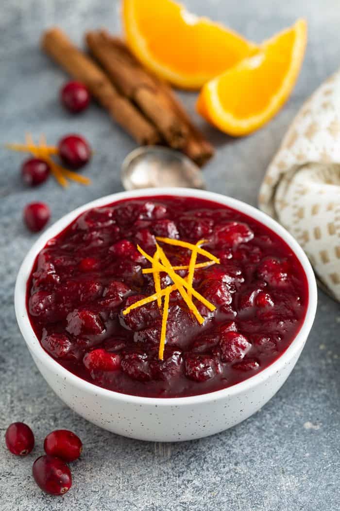 Cranberry sauce in a white bowl, garnished with orange zest