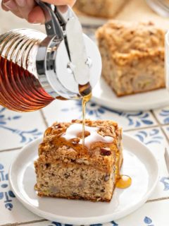 Maple syrup being poured over the top of a slice of banana coffee cake