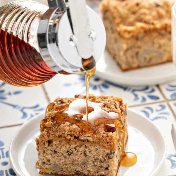 Maple syrup being poured over the top of a slice of banana coffee cake