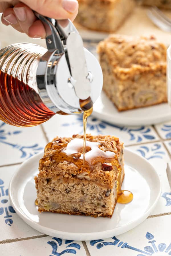 Maple syrup being poured over the top of a slice of banana coffee cake