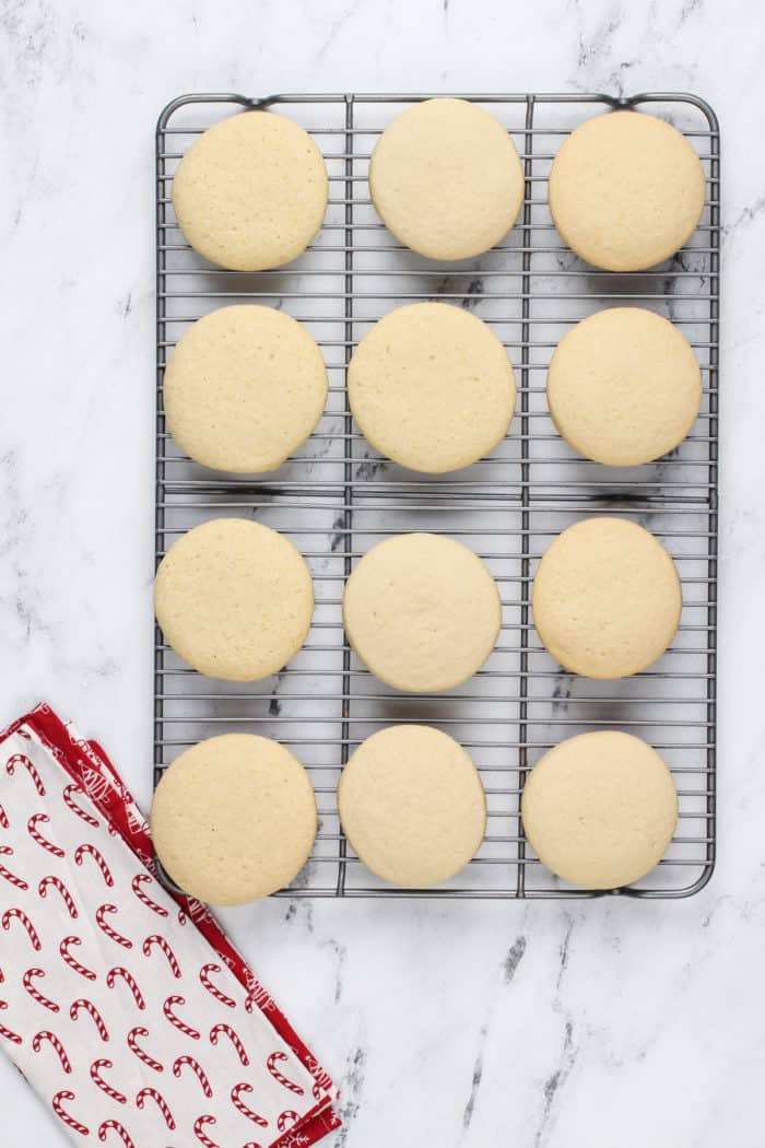 Unfrosted sour cream sugar cookies cooling on a wire rack.