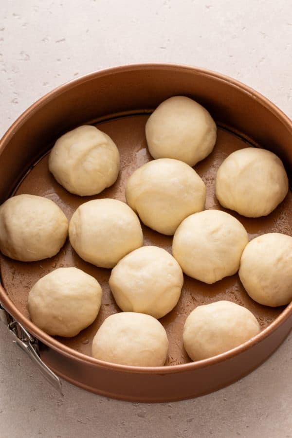 Classic dinner rolls arranged on a baking pan, ready to rise.