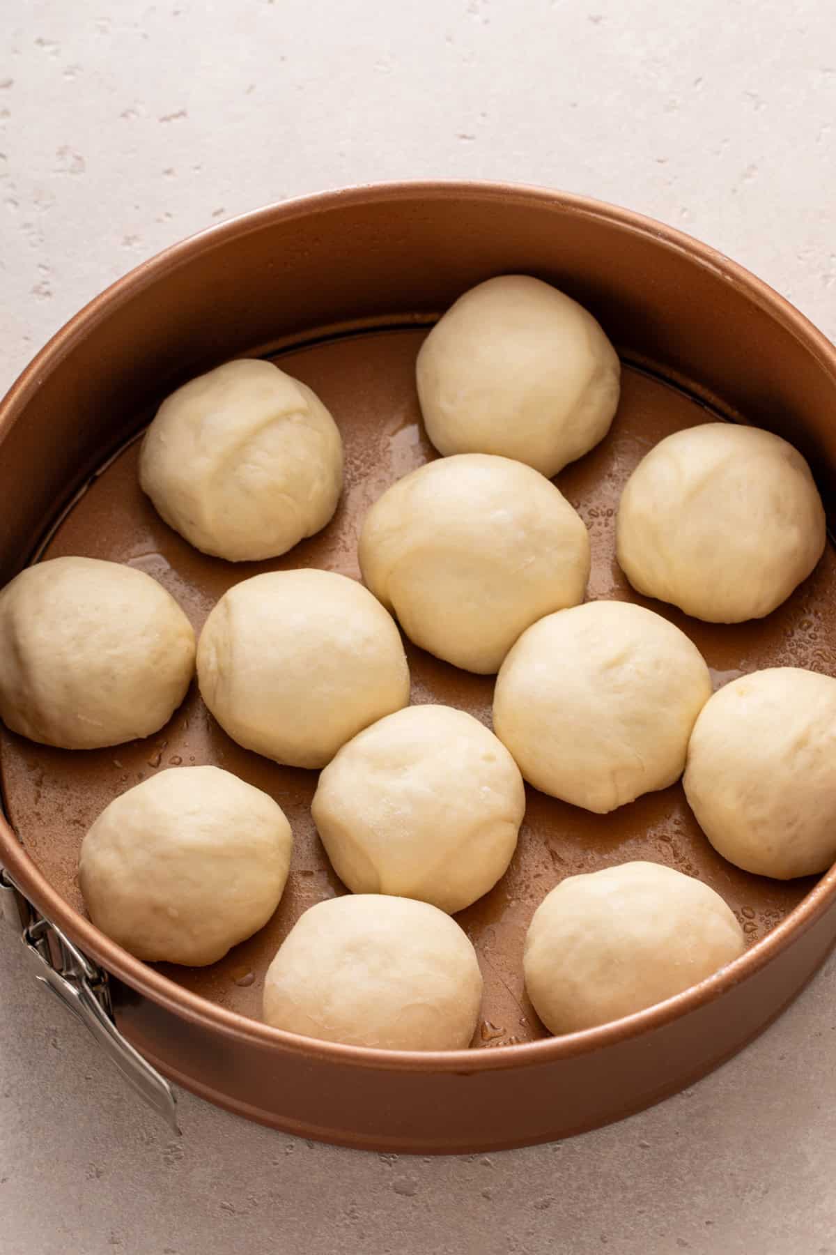 Classic dinner rolls arranged on a baking pan, ready to rise.
