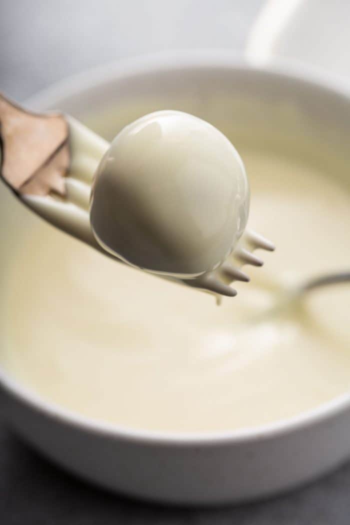 Oreo ball freshly coated in white candy melts on a fork