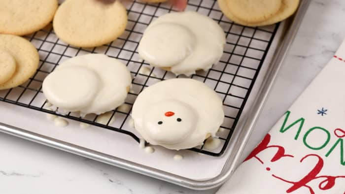 Melted snowman cookies being coated with candy melts.