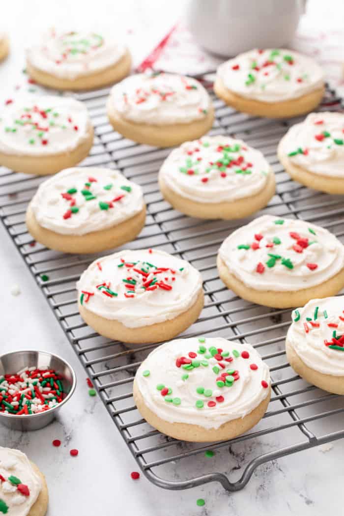 Frosted and decorated sour cream sugar cookies lined up on a wire rack.