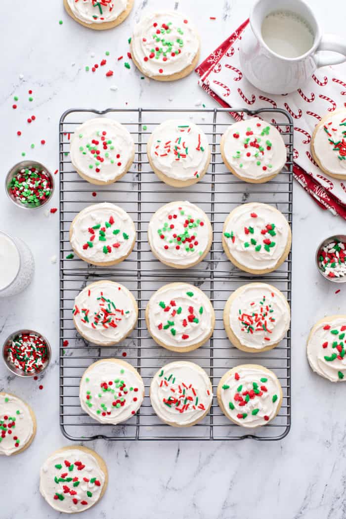 Overhead view of sour cream cookies topped with christmas sprinkles on a wire rack.