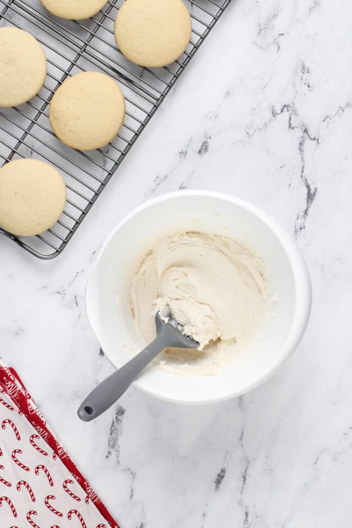 Frosting for sour cream sugar cookies in a white mixing bowl.