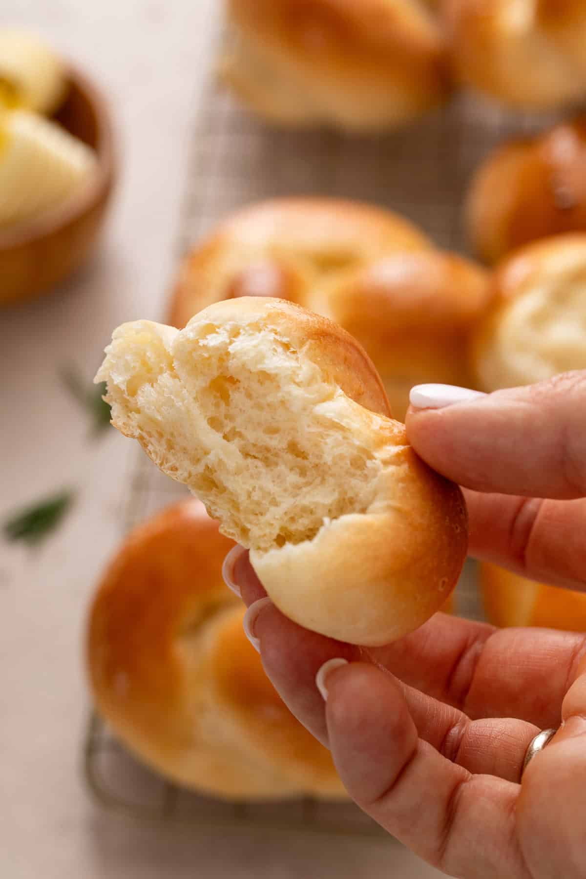 Hand holding up a halved brown and serve roll.