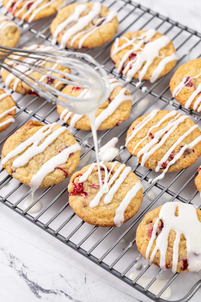 Whisk drizzling icing on top of orange cranberry cookies
