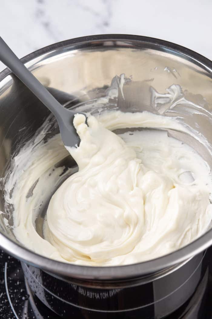 White candy melts being melted in a metal bowl.