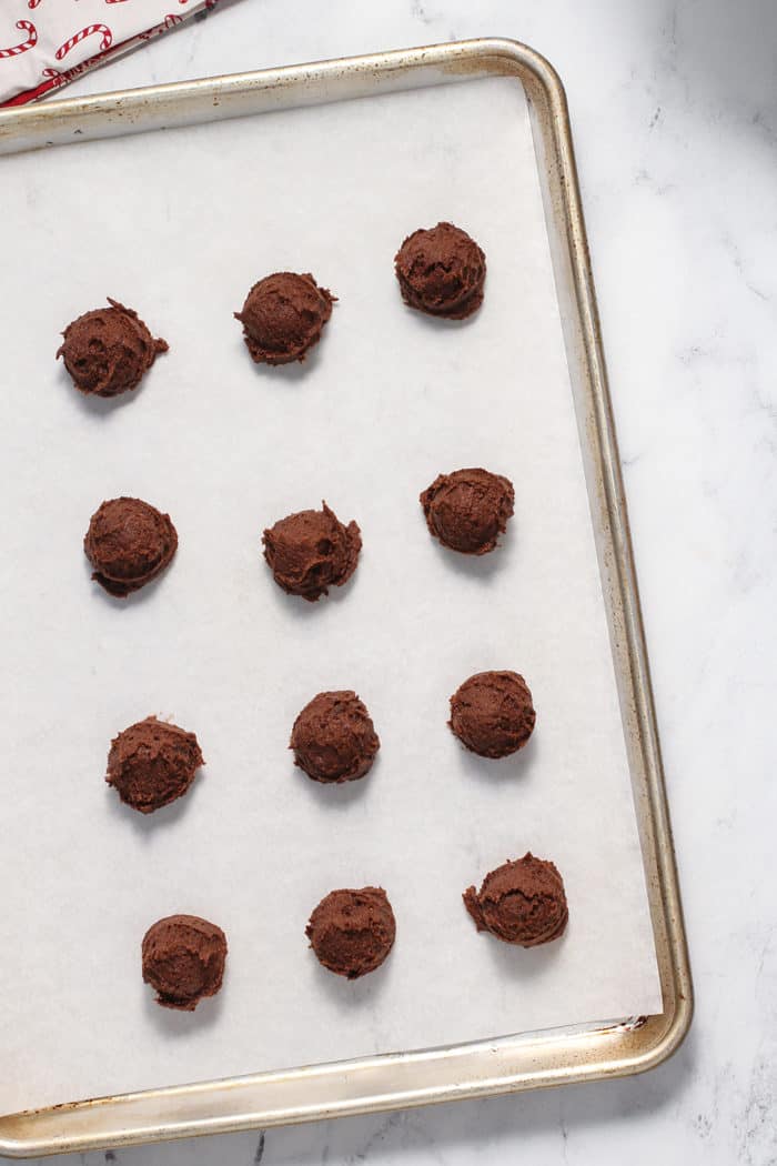 Balls of mocha cookie dough on a parchment-lined baking sheet, ready to be baked