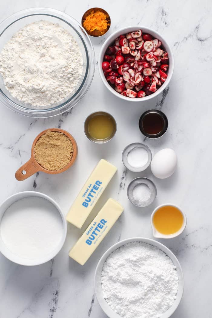 Orange cranberry cookie ingredients arranged on a marble countertop