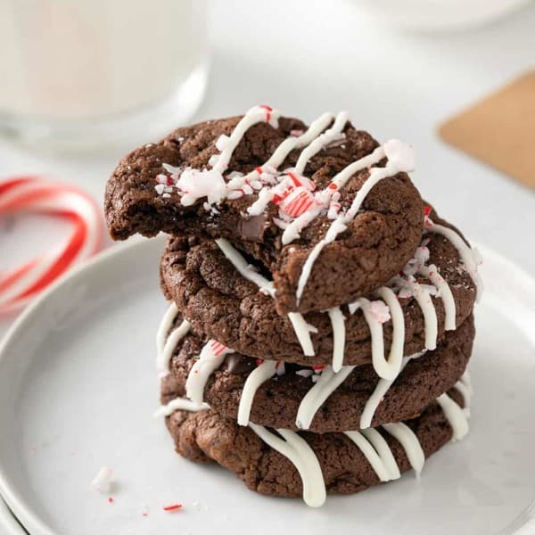 Four peppermint mocha cookies stacked on a white plate. The top cookie has a bite taken out of it