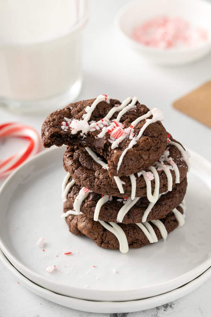 Four peppermint mocha cookies stacked on a white plate. The top cookie has a bite taken out of it