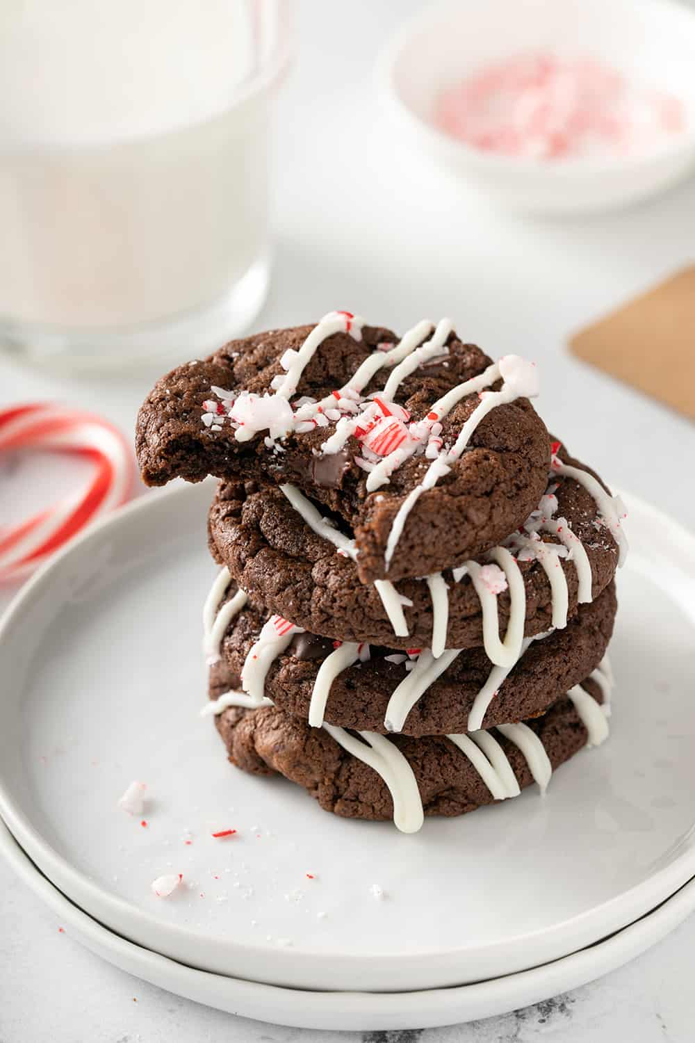 Four peppermint mocha cookies stacked on a white plate. The top cookie has a bite taken out of it