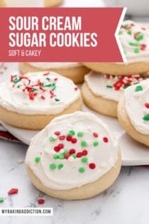 Assortment of sour cream sugar cookies, topped with red and green sprinkles, arranged on a white platter. Text overlay includes recipe name.