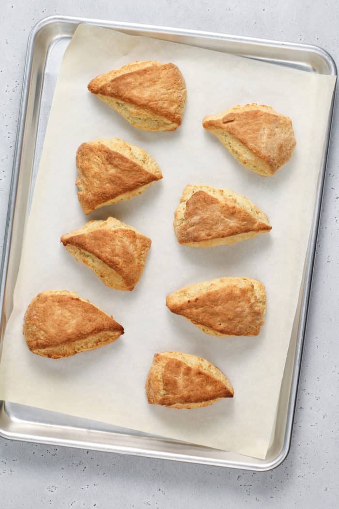 Baked vanilla bean scones on a parchment-lined baking sheet.