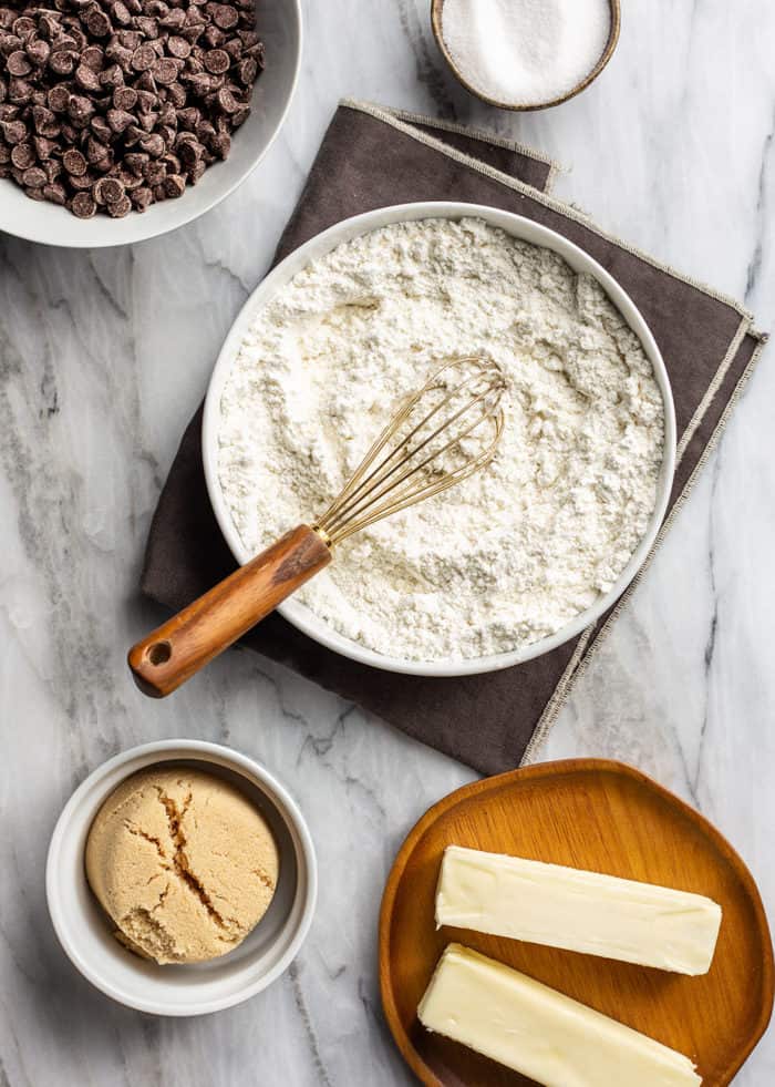 Bowl of flour for pudding cooking surrounded by bowls of chocolate chips, brown sugar, and butter