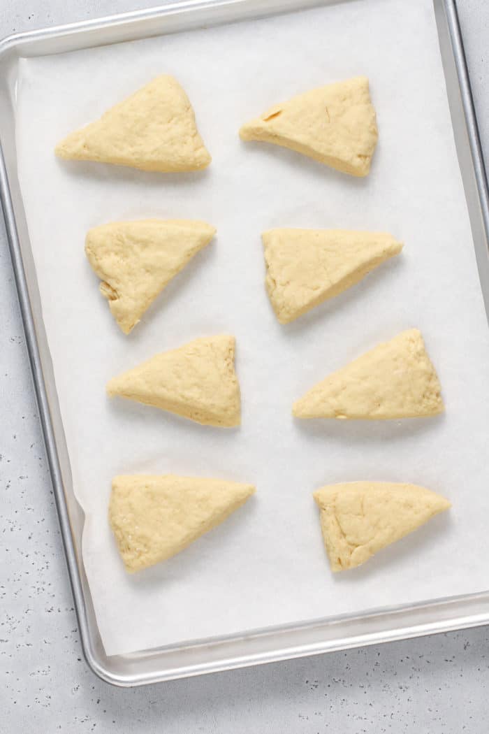 Unbaked vanilla bean scones set on a parchment-lined baking sheet, ready to go in the oven.