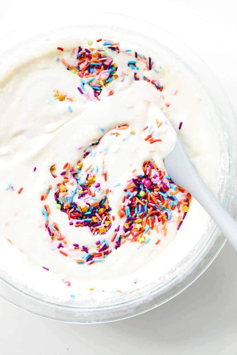 Spoon stirring sprinkles into cupcake batter for funfetti cupcakes