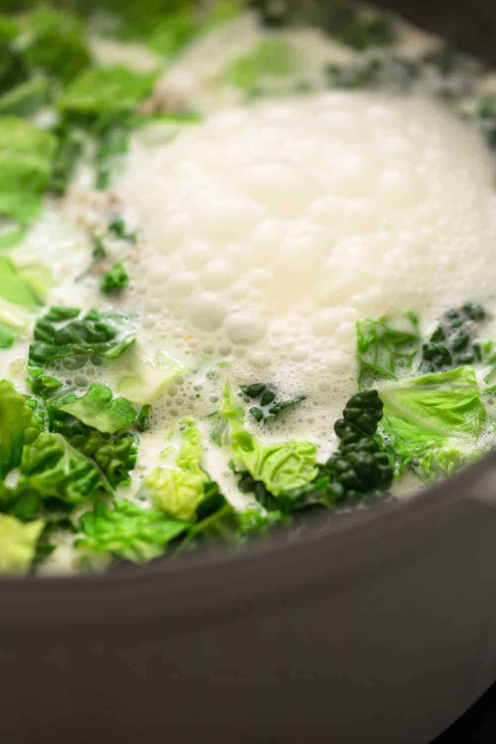 Close up view of zuppa toscana simmering in a cast iron dutch oven