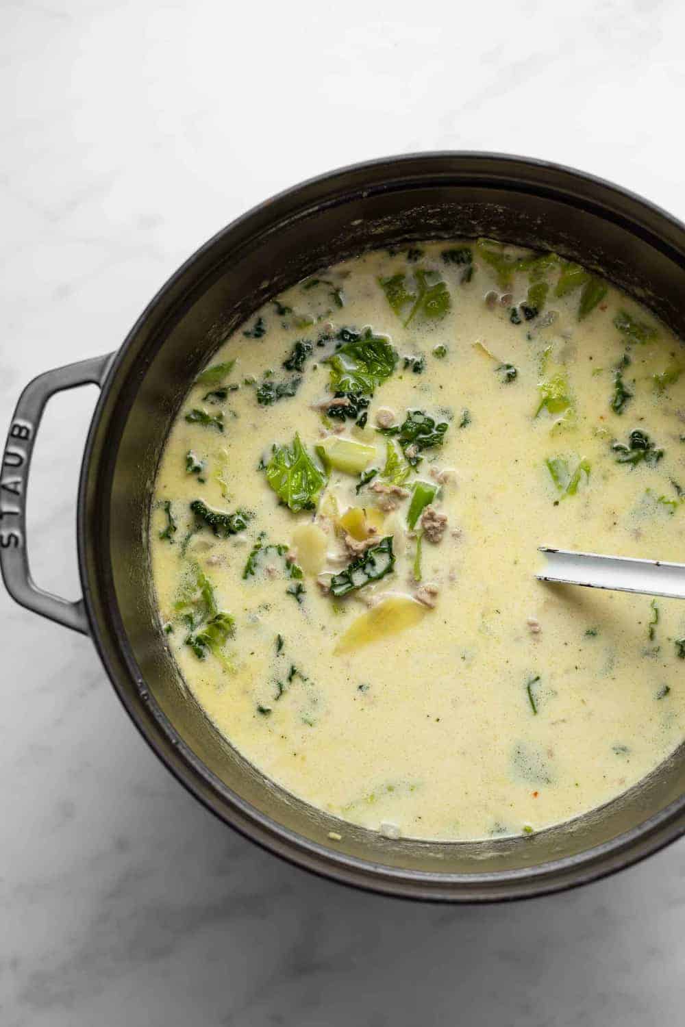 Zuppa toscana in a cast iron dutch oven on a marble surface