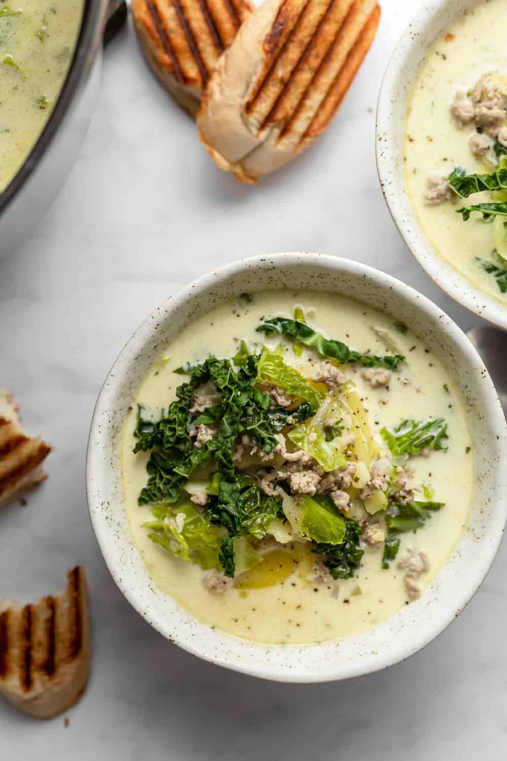 Overhead view of a bowl of zuppa toscana alongside grilled bread