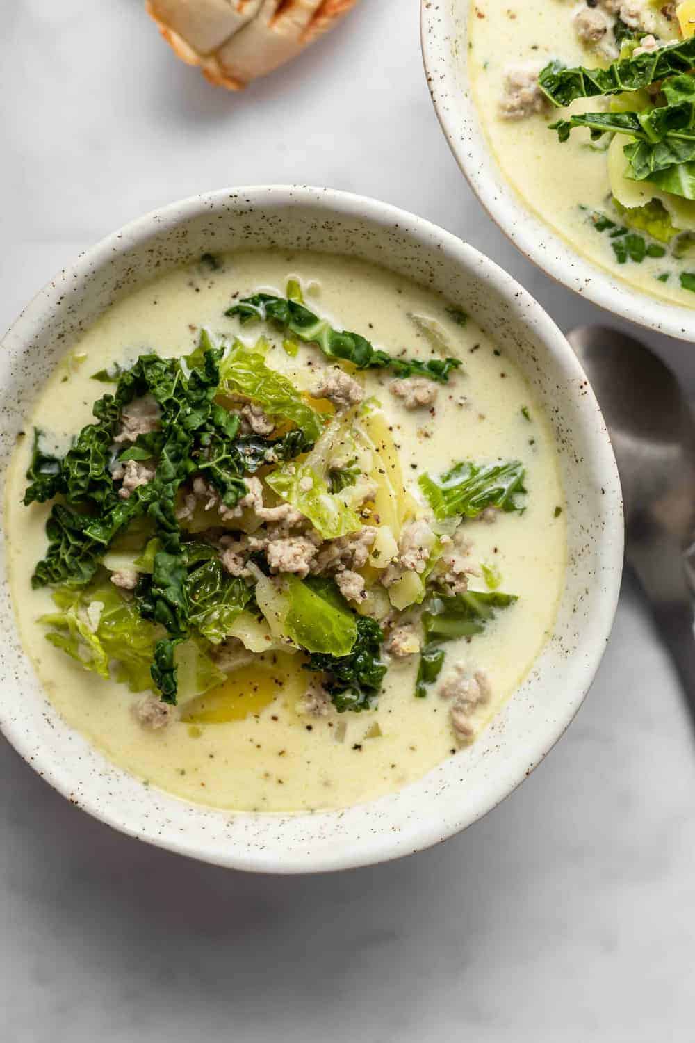 Close up of a bowl of zuppa toscana on a marble surface