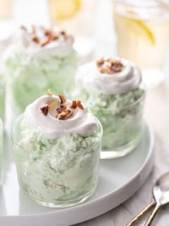 Three small serving dishes filled with watergate salad set on a white platter