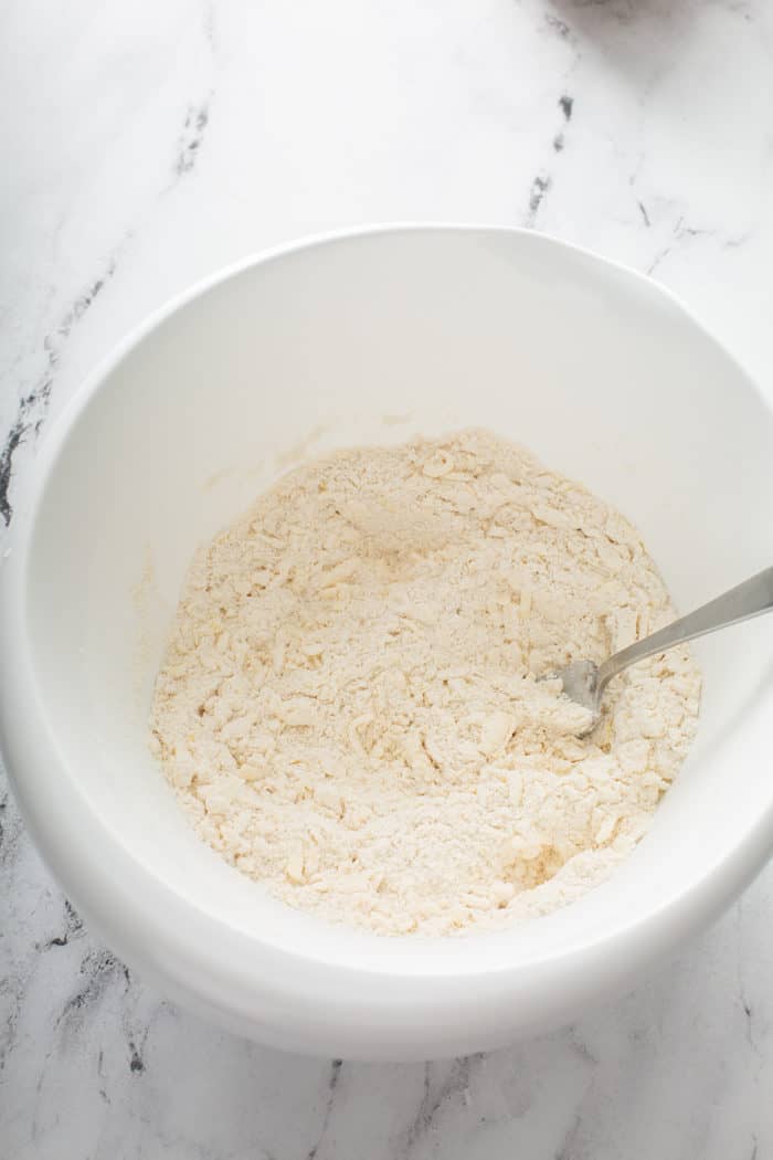 Crumbly butter and flour mixture for scones mixed together in a white mixing bowl