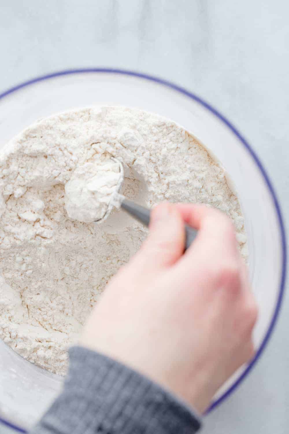 Hand using a spoon to fluff and stir the flour in a bowl