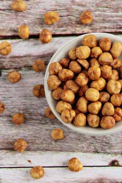 Skinned hazelnuts overflowing in a bowl on a wood surface