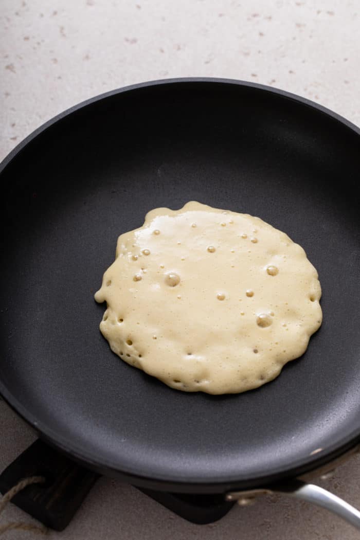 Gluten-free pancake cooking in a nonstick skillet.