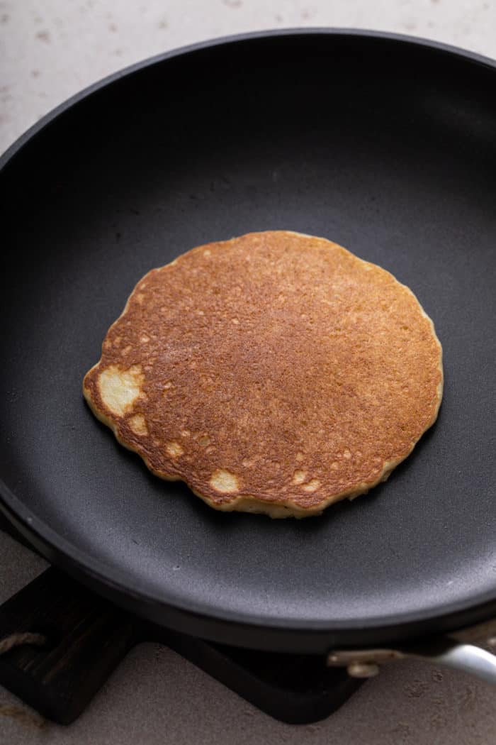 Flipped gluten-free pancake in a nonstick skillet.