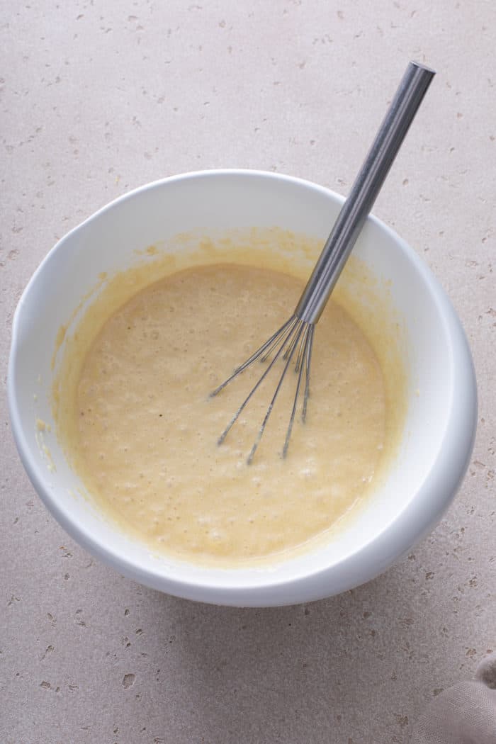 Gluten-free pancake batter being whisked in a white mixing bowl.