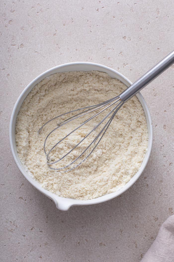 Dry ingredients for gluten-free pancakes being whisked together in a ceramic bowl.