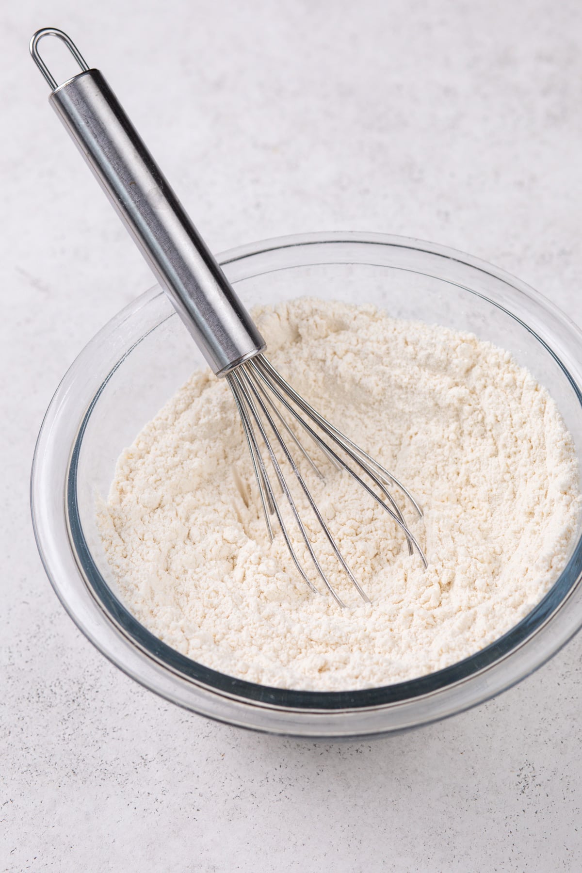 Dry ingredients for cookies whisked together in a glass bowl.