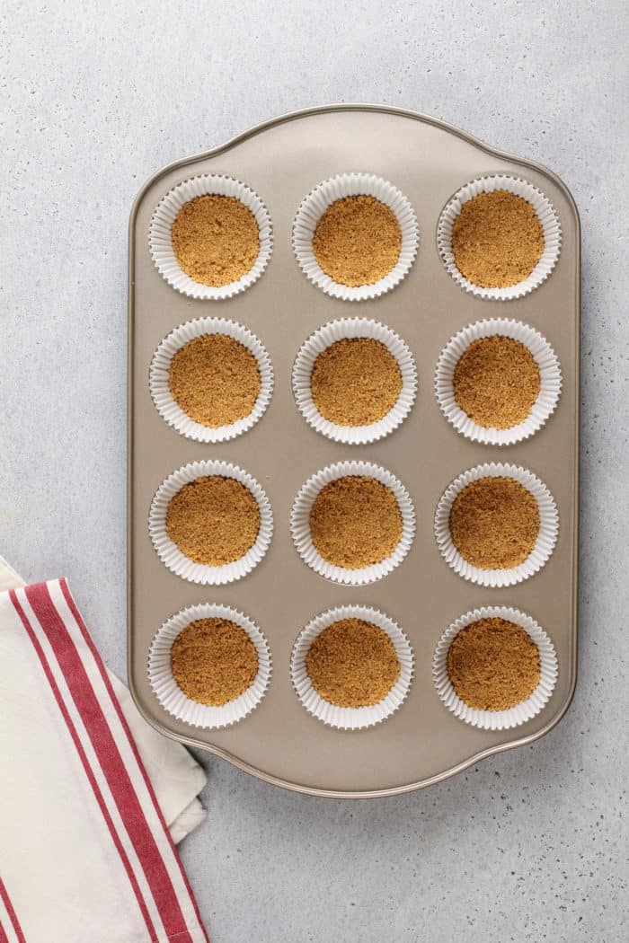 Graham cracker crust pressed into the bottom of cupcake pan wells for s'mores cupcakes.